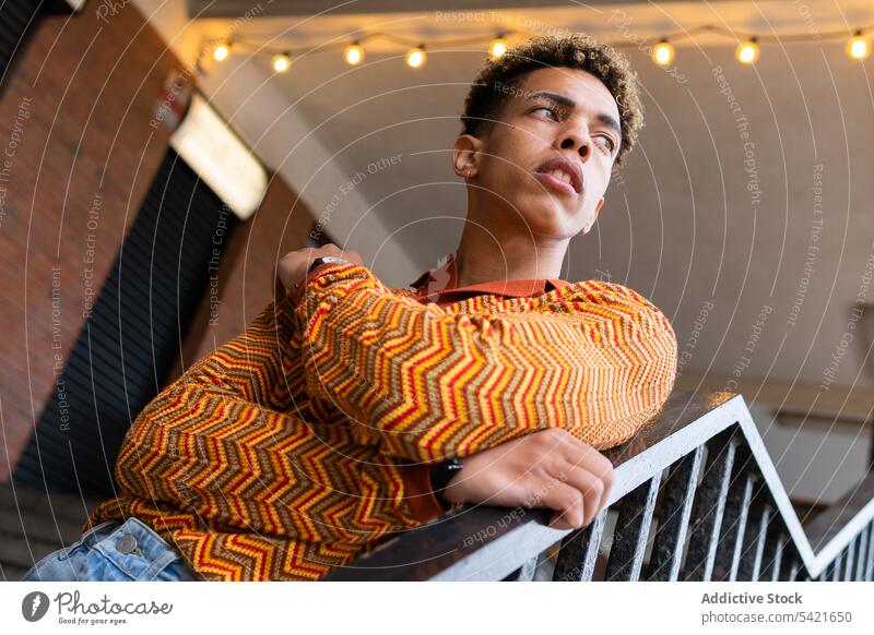 Thoughtful stylish ethnic man in colorful shirt style trendy thoughtful fashion pensive stripe outfit modern young male curly hair afro confident handsome