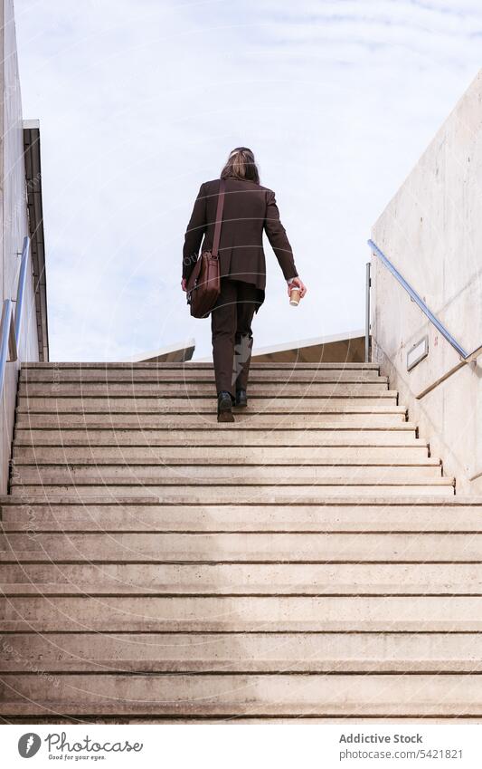 Elegant man in suit walking upstairs in city businessman step climb urban classy style coffee modern elegant briefcase bag entrepreneur success concept