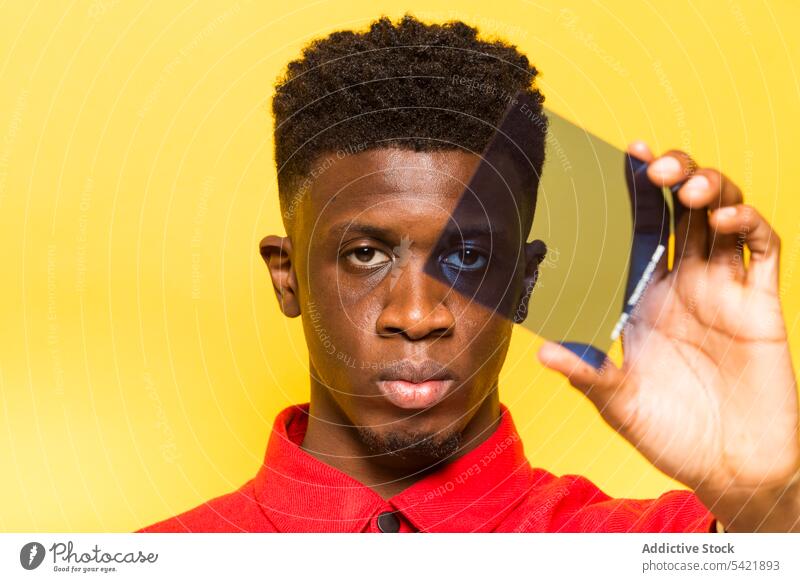 Black man looking at camera through light filter color style studio model serious bright trendy male ethnic black african american vivid confident appearance