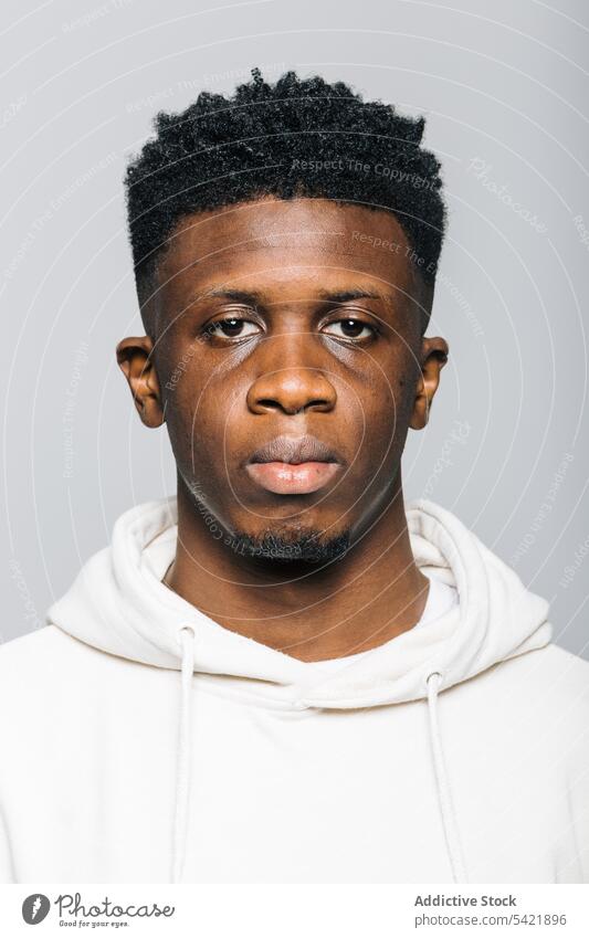 Serious black man in white hoodie serious confident afro portrait human face gaze male young african american stare hipster informal model masculine brutal