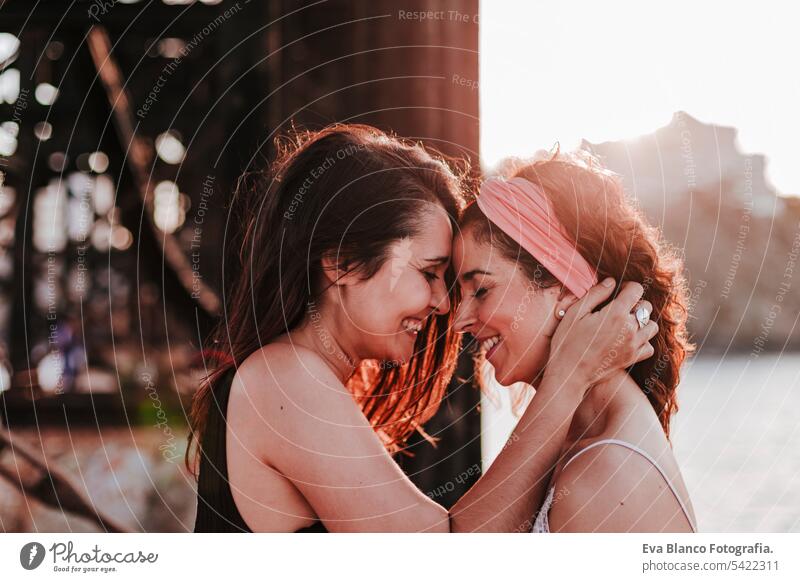 young lesbian couple hugging at sunset outdoors. Lifestyle and pride concept. love is love friends casual lifestyle gay urban cheerful girlfriend standing