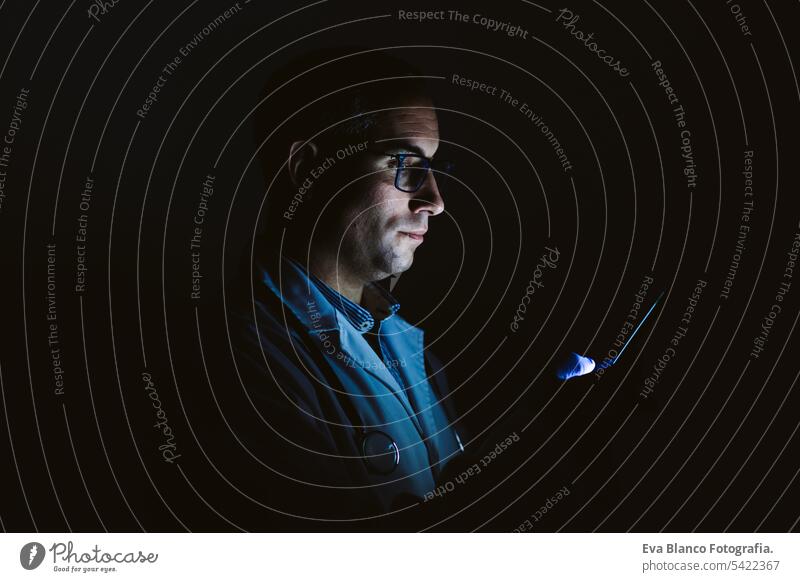 doctor man indoors, using mobile phone. Wearing protective gloves, mask and stethoscope. coronavirus covid-19 concept internet tecgnology dark corna virus