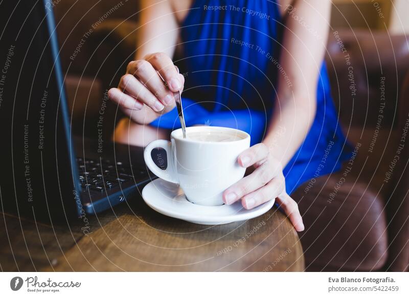 top view of a young beautiful woman writing on laptop, coffee besides. Casual blue dress. Modern life indoors hipster college computer display notebook looking