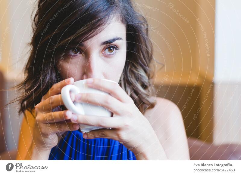 young beautiful woman enjoying a cup of coffee in a cafe. laptop besides. Casual blue dress. Modern life indoors morning holding beauty girl adult lovely joyful