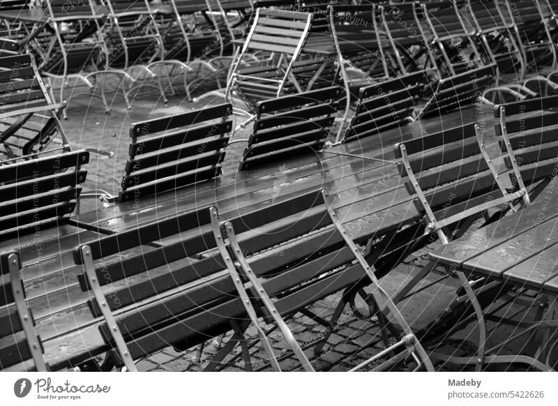 Bistro chairs and wooden tables in rainy weather at shaft XII of the Unesco World Heritage Zollverein Coal Mine Industrial Complex in the Stoppenberg district of Essen in the Ruhr region in neo-realistic black and white