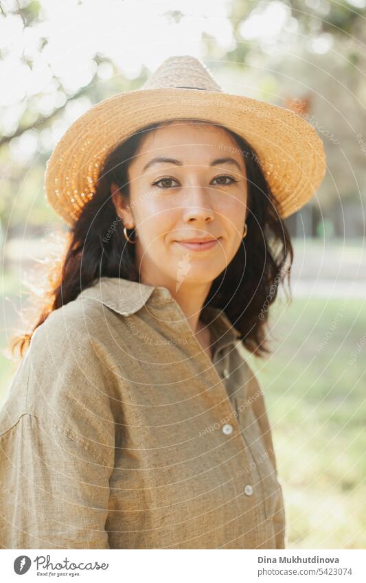 beautiful 30 year old millennial woman face closeup in hat and olive green linen shirt in the park with soft sunlight autumn or summer portrait Woman