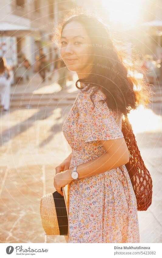 beautiful brunette woman tourist in European city smiling at sunset, walking on the street. Female solo traveler looking to the camera in Valencia, Spain.