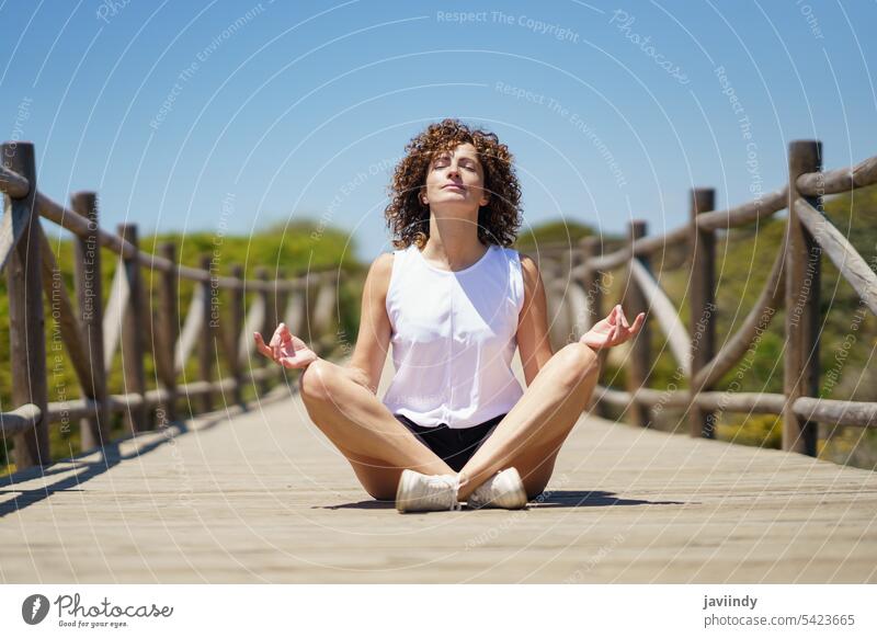 Calm woman sitting in lotus pose on pier yoga meditate asana calm nature zen wellness energy mindfulness spirit concentrate position healthy relax vitality