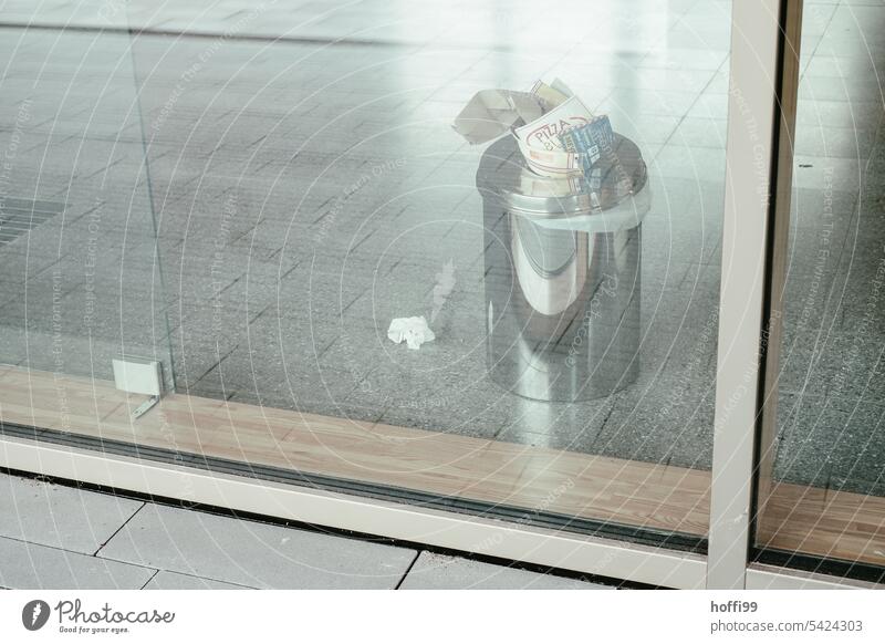 Overfilled trash can in an entrance area behind glass Mülleinmer Entrance Full trash can Way out Waste management Trash container remnants waste Residual waste