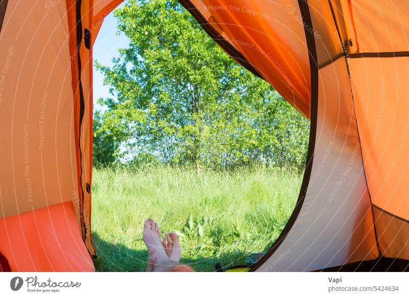 Man resting inside orange tent camp vacation camping legs nature view grass foot people recreation forest tree landscape adventure tourism summer travel hiking