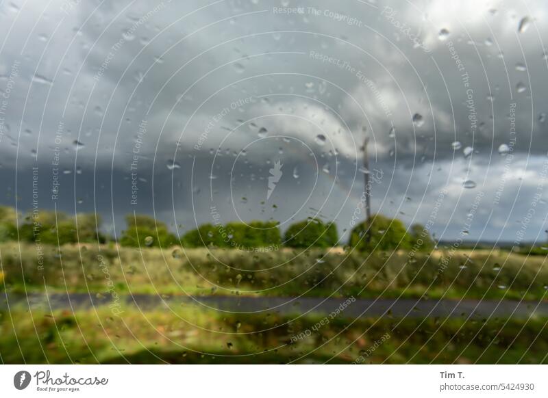 Car ride in rain and sun Glass Landscape Rain Drop Driving Drops of water Wet Window Window pane Close-up Deserted raindrops Weather blurriness Colour photo