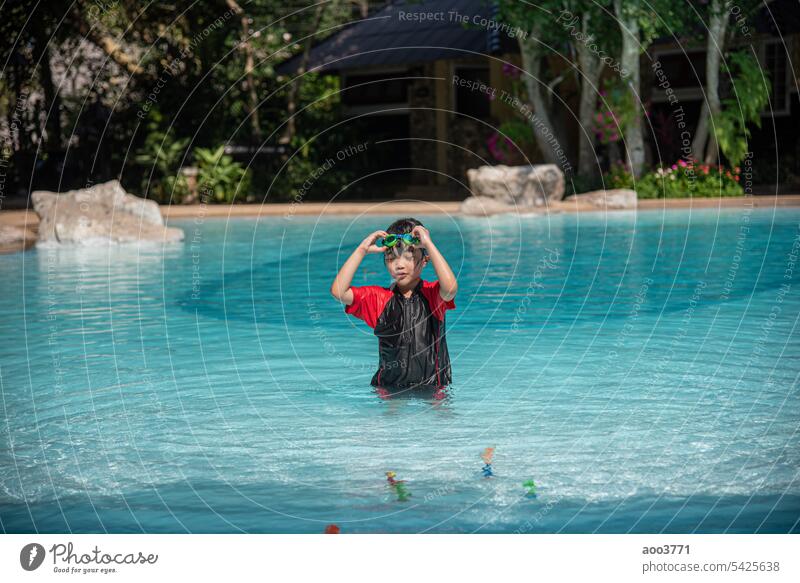 Asian little girl in swimsuit playing with toys at swimming pool happily and having fun. young asian playtime recreation leisure summer water splashing vacation