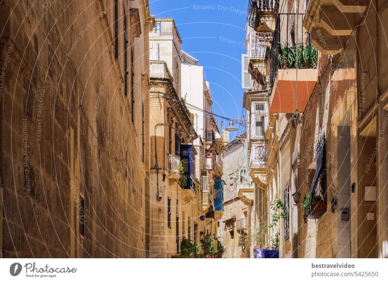 Traditional Maltese limestone buildings with coloured balconies in the vibrant alleys of the old city Birgu, Citta Vittoriosa without crowd.