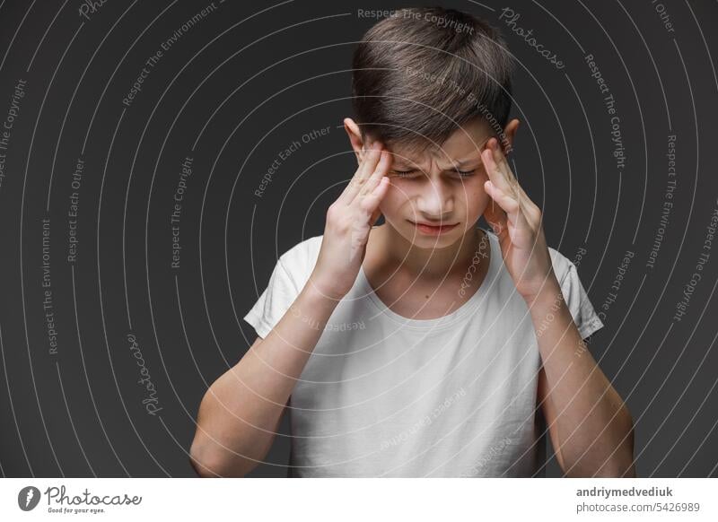 Handsome teenager boy wearing casual white t-shirt standing over isolated background suffering from headache desperate and stressed because pain and migraine. Hands on head.