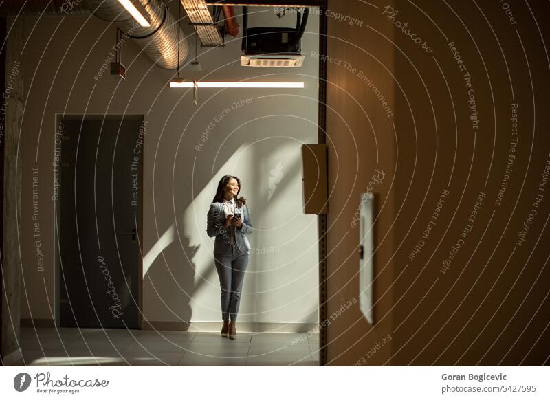 Young business woman using mobile phone in the office hallway caucasian professional businesswoman female people person confident talking cellphone