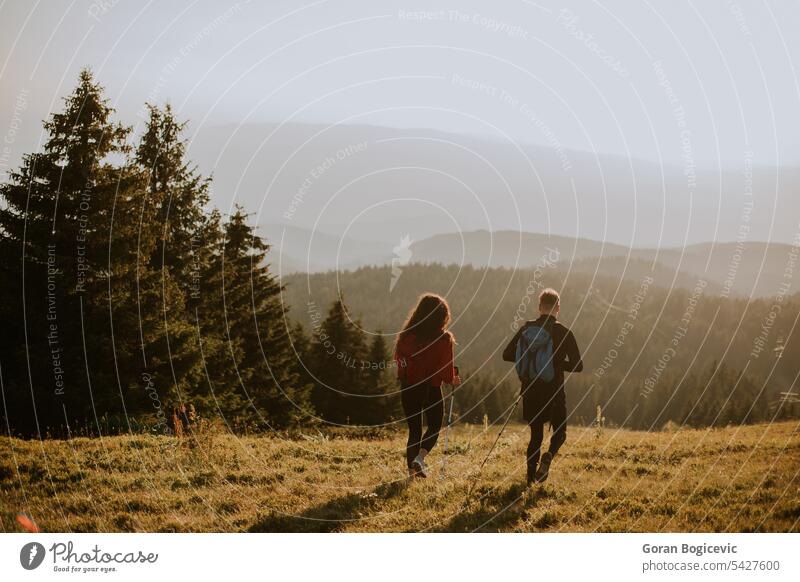 Smiling couple walking with backpacks over green hills active activity adults adventure backpacker backpacking boyfriend caucasian countryside curly female