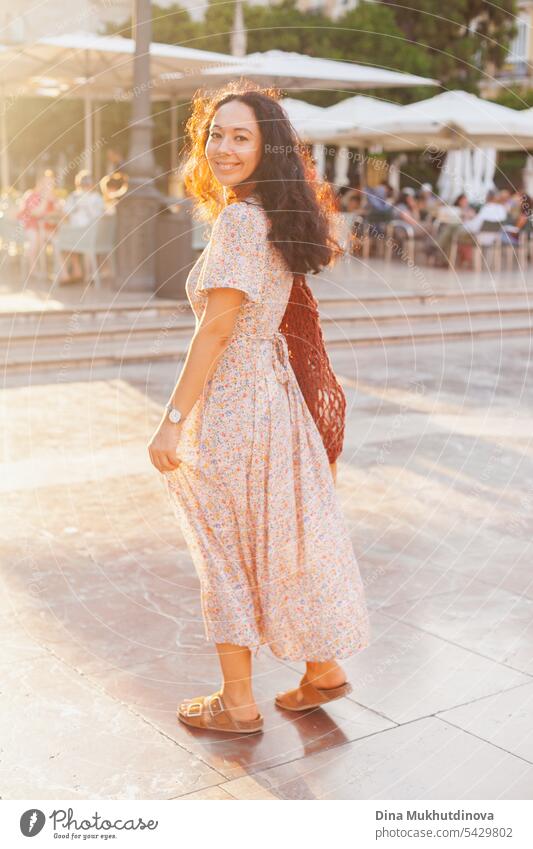 Beautiful female tourist at sunset in Valencia, Spain. Brunette woman summer dress with trendy crochet bag walking the street. beautiful gorgeous Tourism