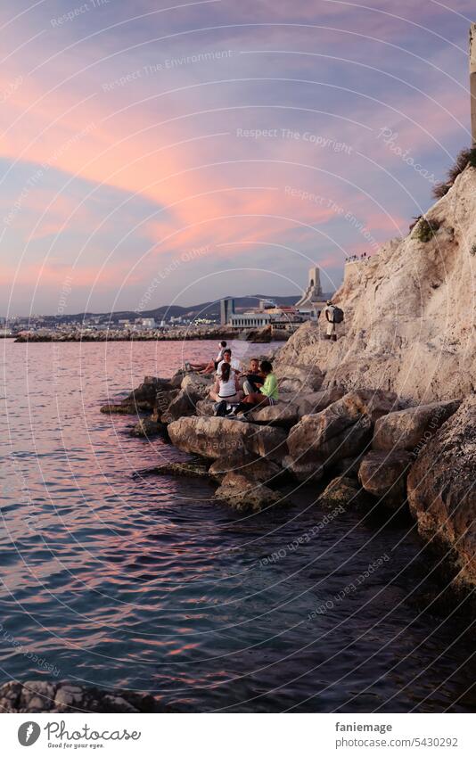 Rocks of Malmousque with evening bathers with the Monument aux héros de l'armée d'Orient et des terres lointaines in the background at sunset Marseille Ocean