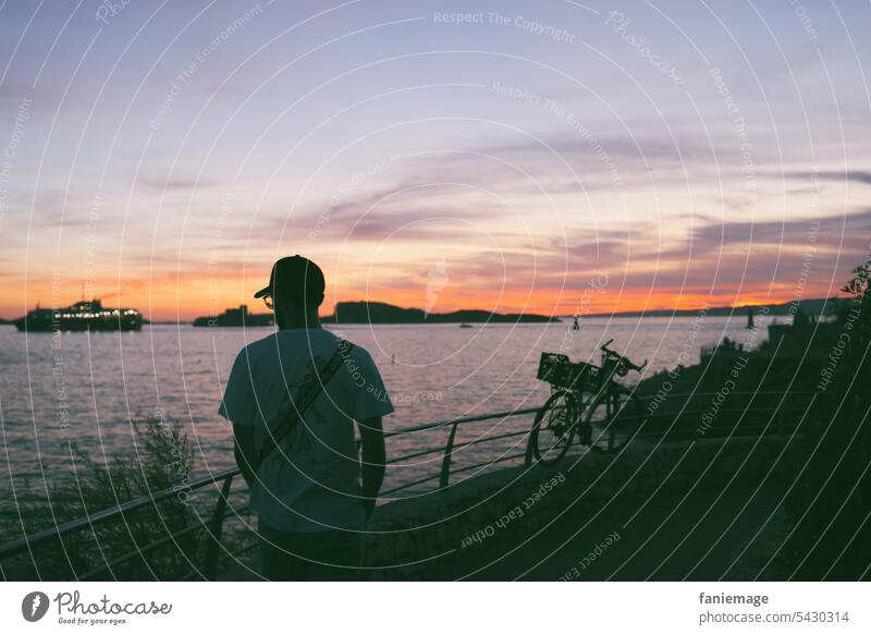 Spaziergänger bei Malmousque, Marseille, im Sonnenuntergang mit Schiff und Îles du Frioul im Hintergrund Spaziergang Abendrot Mann Kappe Brille Felsküste