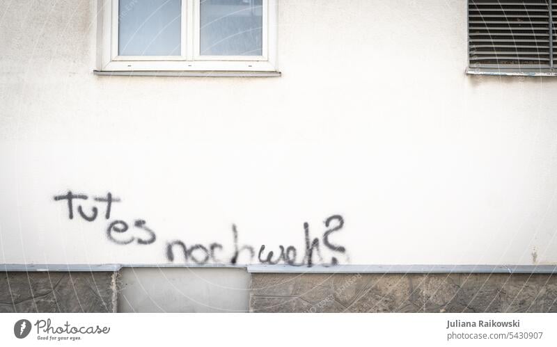 Graffiti with inscription "Does it still hurt?" Wall (building) Wall (barrier) Characters Facade Exterior shot Colour photo Deserted Day Town Sign