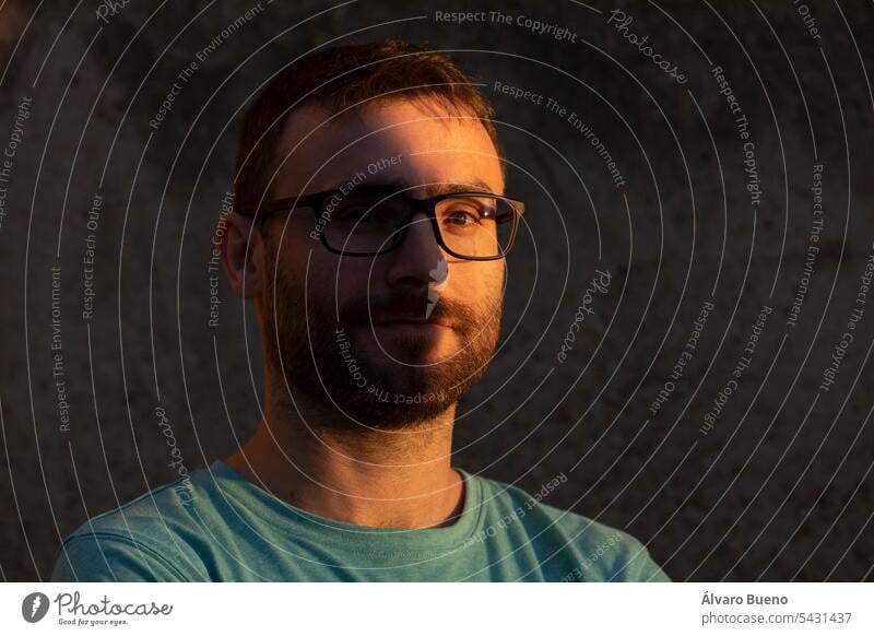 Portrait of a man looking at the camera, with beard and glasses, a bit hipster, in the shadows of the sunset male portrait person adult guy lifestyle face