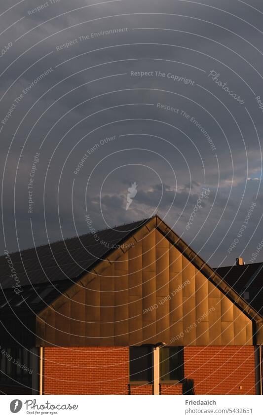 House gable shining in golden light under dark stormy sky House (Residential Structure) house gables Storm clouds dark sky golden hour Light Evening Sky Sun