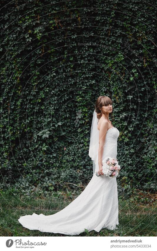 Beautiful bride in fashion wedding dress on natural background.The stunning young bride is incredibly happy. Wedding day. A beautiful bride portrait. flower