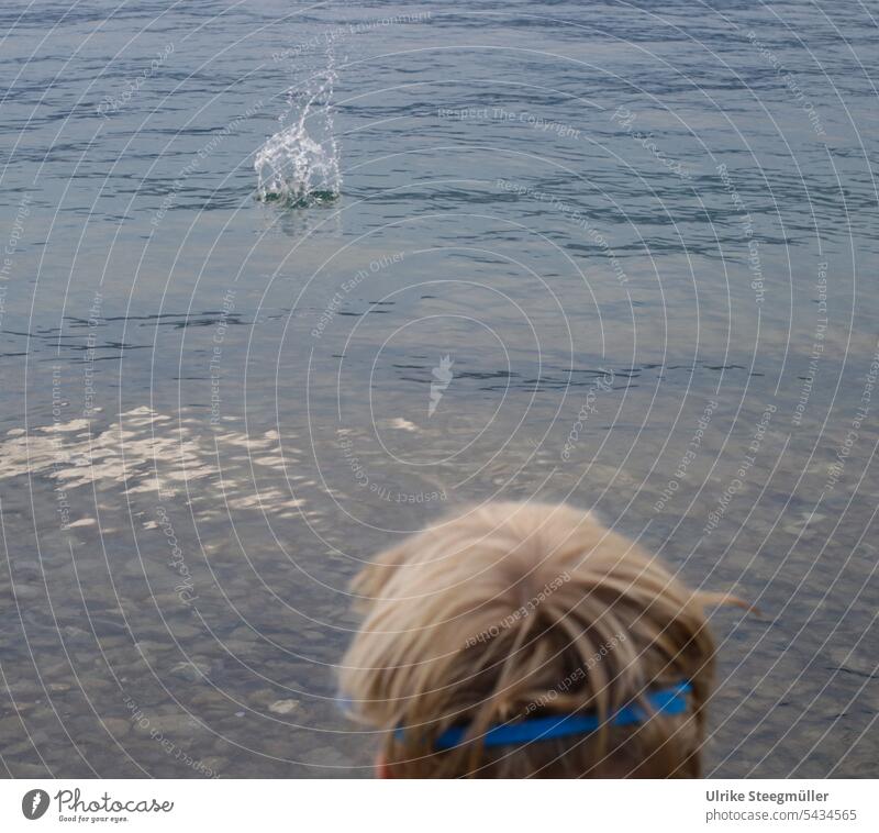 Child throws a stone into the lake Vacation with children Stone Lake Lago Maggiore Italy Summer vacation be afloat Dive Diving goggles stone's throw