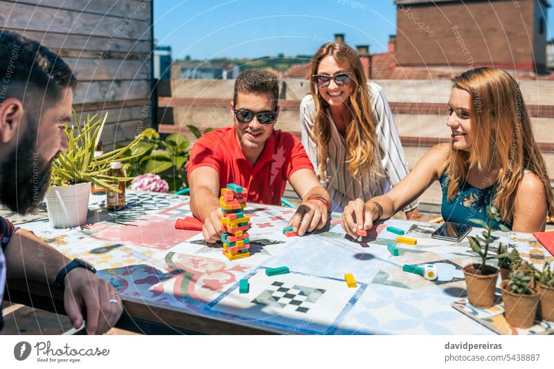 Group of office workers playing with jenga game on terrace group colleague break pause smile having fun relaxing resting rooftop teamwork together happy