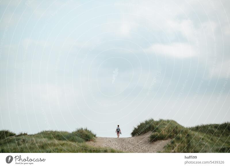 a man walks over a dune towards the sea duene Marram grass Beach dunes Vacation & Travel Nature coast Landscape Sand Sky North Sea North Sea coast Clouds