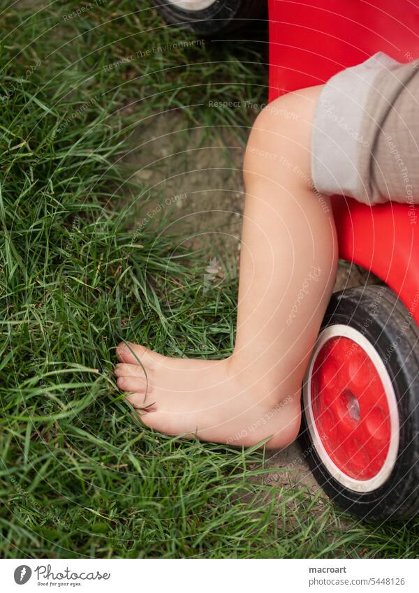 Child on a slide car Toddler Childlike feet Barefoot Playing driven Lawn Meadow out Weather Summer Legs body part play nature naturally Joy Parenting