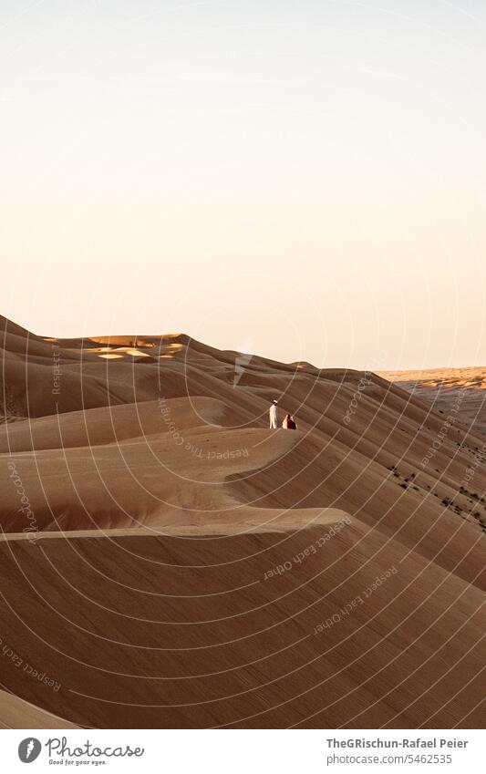 Young man stands on the edge of a dune and watches the sunset Sand Exterior shot Colour photo Nature Sun Tourism Wahiba Sands Oman Omani desert Landscape Desert