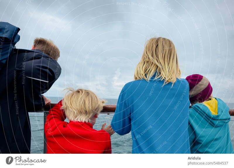 Father with three children looks over the railing of a ferry at the blue-gray Baltic Sea Families Ferry ship boat Railing Navigation Water Ocean Watercraft