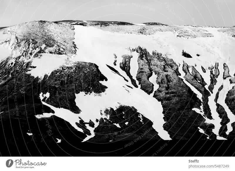 View of a mountain side with snowmelt in Iceland Snow melt Snow forms Hill side Mountain side shape residual snow Dark North Iceland Nordic somber Dark coloring