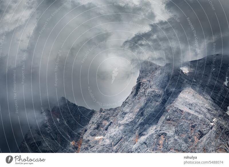 dramatic storm clouds over Zugspitze peak mountain alpine Alps Zugzpitze rock top stone sky cloudscape fog weather rain shower dark summer season seasonal view