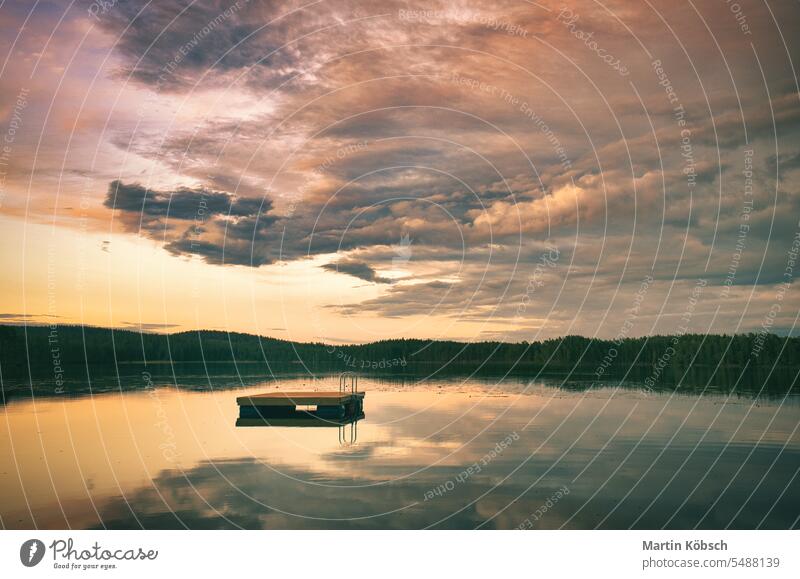 Swimming island in Sweden on a lake at sunset. Clouds reflected in the water. swimming island wooden island reflection summer vacation silence swimming fun