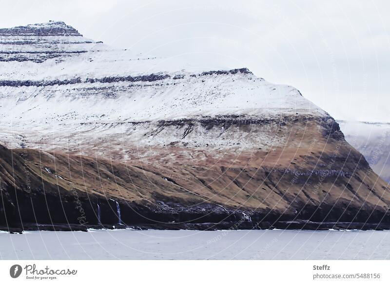 Faroe Island covered with snow färöer Faroe Islands Sheep Islands rocky cliff Gray Snow Rock North rock island snow-covered residual snow Atlantic Ocean oceanic