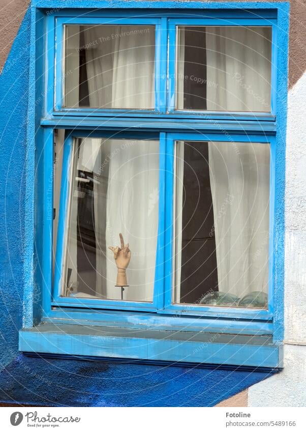 I look out of the window and look across the street. In the window opposite, the outstretched middle finger of a wooden hand stretches out toward me. Ha, I laughed so hard!