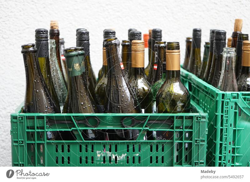 Folding boxes in green plastic with empty wine bottles with raindrops in the backyard of the restaurant in the Braubachstraße in the city center of Frankfurt am Main