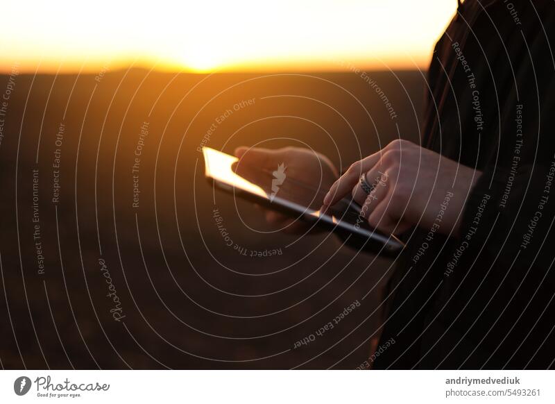 Cropped shot of male farmer's hands use digital tablet on plowed field for control of soil quality, land readiness for sowing crops and planting vegetables. Smart farming technology and agriculture