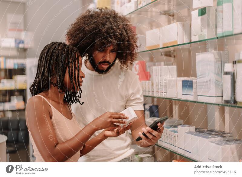 Black couple reading information on cellphone at drugstore boyfriend girlfriend pharmacy buy man woman smartphone medicine bottle package health care shop