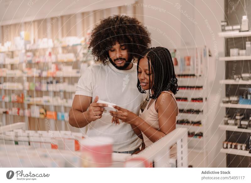 Black couple reading information on medicine package at drugstore boyfriend girlfriend pharmacy buy man woman health care shop purchase antibiotic client