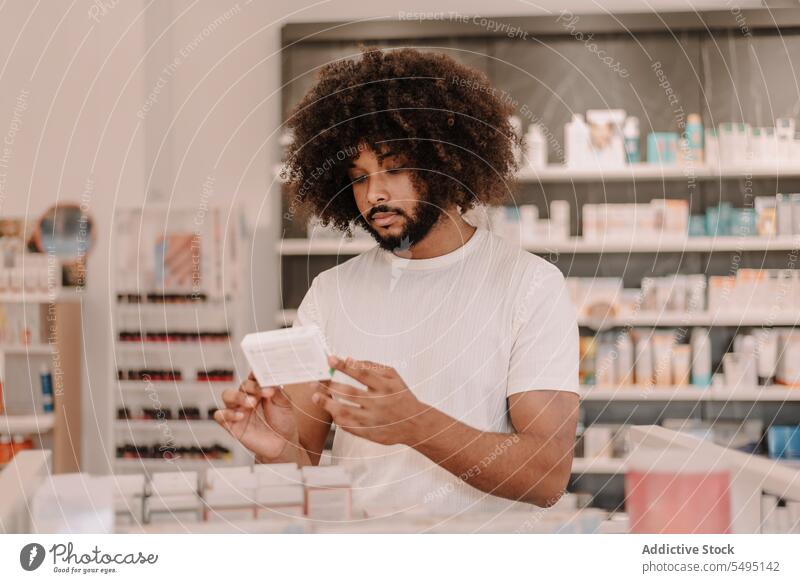 African American man with afro hair reading label on prescribed medicine at pharmacy buy information customer prescription drugstore lifestyle health care