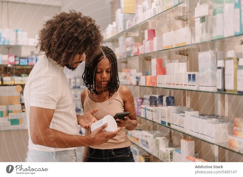 Black couple reading information on cellphone at drugstore boyfriend girlfriend pharmacy buy man woman smartphone medicine bottle customer health care shop