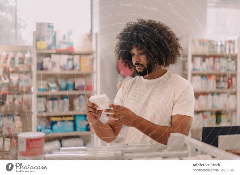 African American man with afro hair reading label on prescribed medicine at pharmacy buy information customer prescription drugstore lifestyle health care