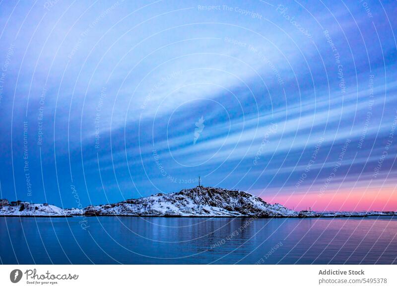 Snowy mountains near sea against cloudy sky at sunset seascape rocky ridge water formation sundown evening winter scenery snow cold freeze lofoten island norway