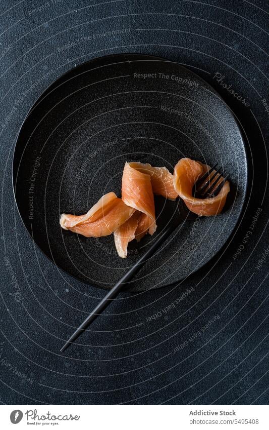 Healthy salmon slice on dark plate dish healthy food black dark background table surface yummy fresh nutrition nutrient fork menu darkness high angle from above