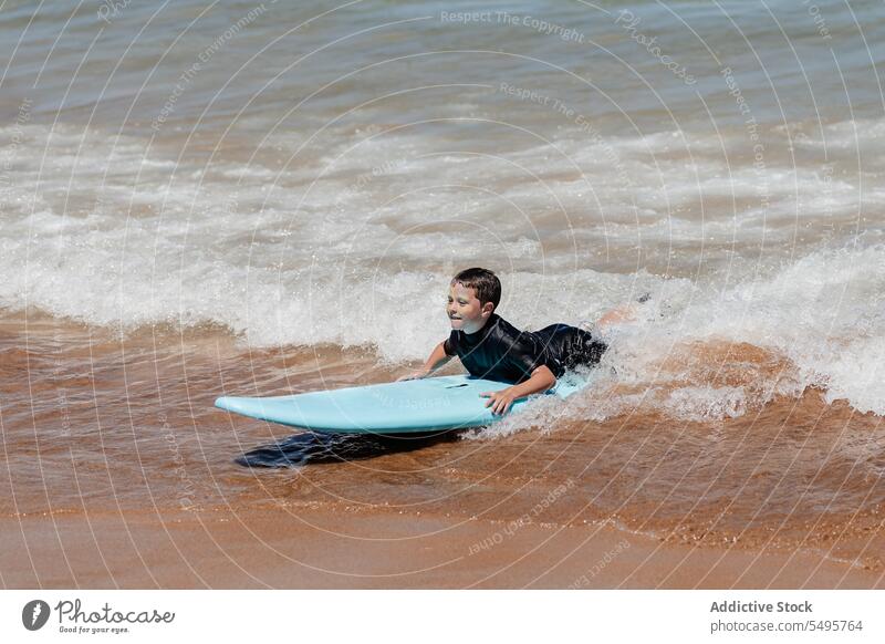 Kid with surfboard in sea boy surfer swim wave lying ocean surfing summer child male vacation seascape nature happy kid together playful water activity hobby