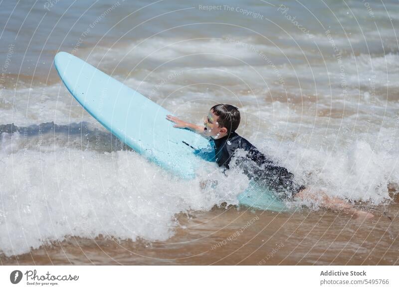 Kid with surfboard in sea boy surfer swim wave lying ocean surfing summer child male vacation seascape nature happy kid together playful water activity hobby