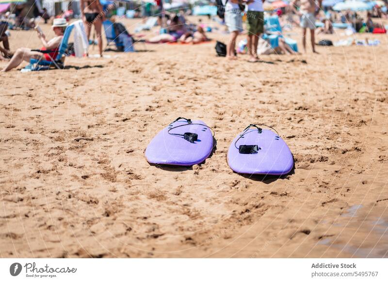 Inflatable body boards on sandy beach with group of people inflatable bodyboards shore seaside relax sunbath vacation resort rest holiday friendship together